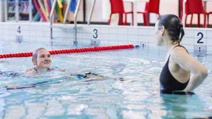 Två badande personer som pratar i bassängen.