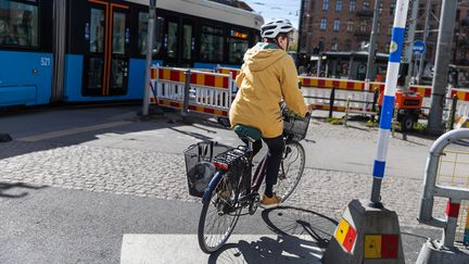 En person som cyklar utmed en spårvagn.