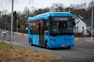 En blå liten flexlinjebuss kör mot kameran. 