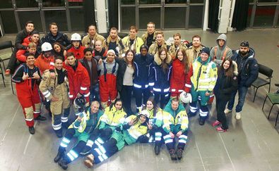 En gruppbild på flera ungdomar i olika uniformer tillsammans med personal som ler mot kameran