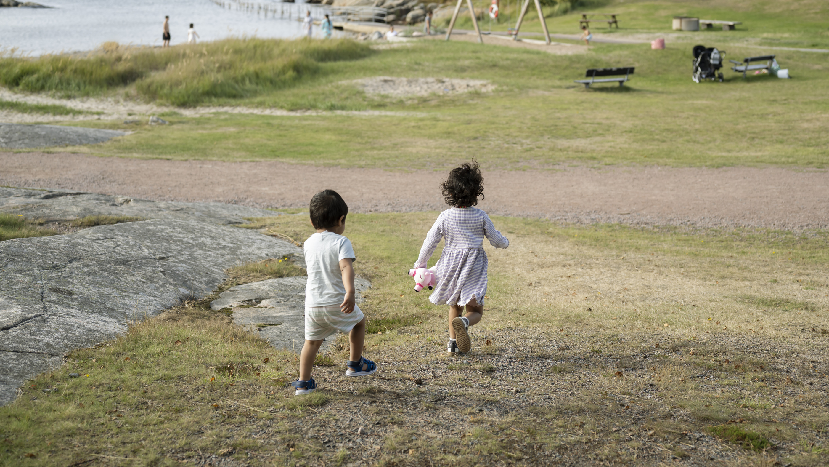 Två barn springer på gräsmatta ned mot havet. Foto: Julia Sjöberg