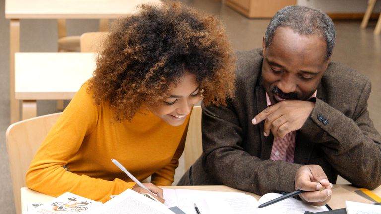 A man and a woman smiling and looking at papers.