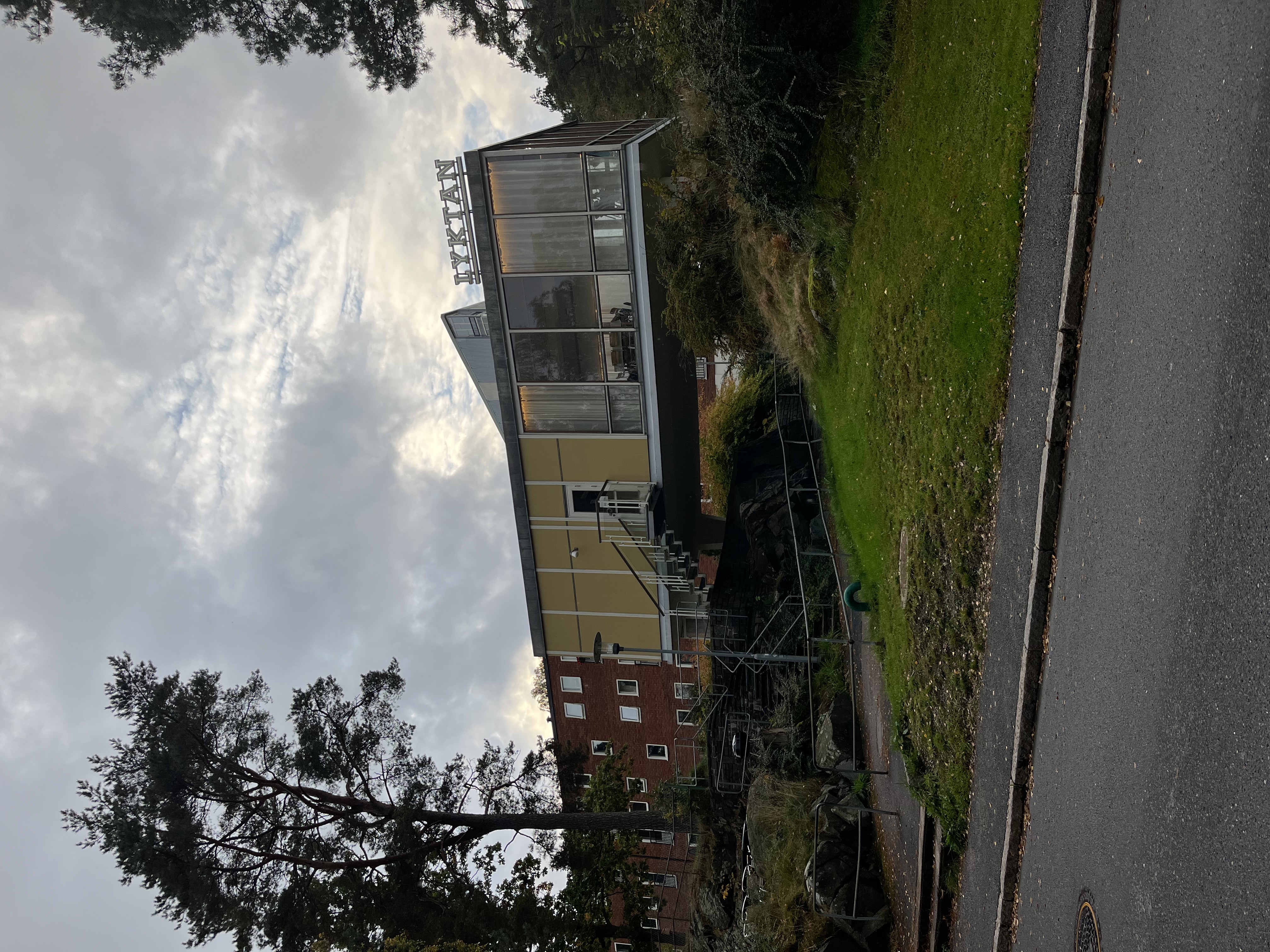 Lyktan i Kortedala som är en gul  byggnad som är placerad över en gångväg. Byggnaden har stora fönster och en neonskylt där det står "Lyktan".