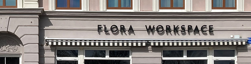 FLora Workspace står med svara friliggande bokstäver på en grå fasad.