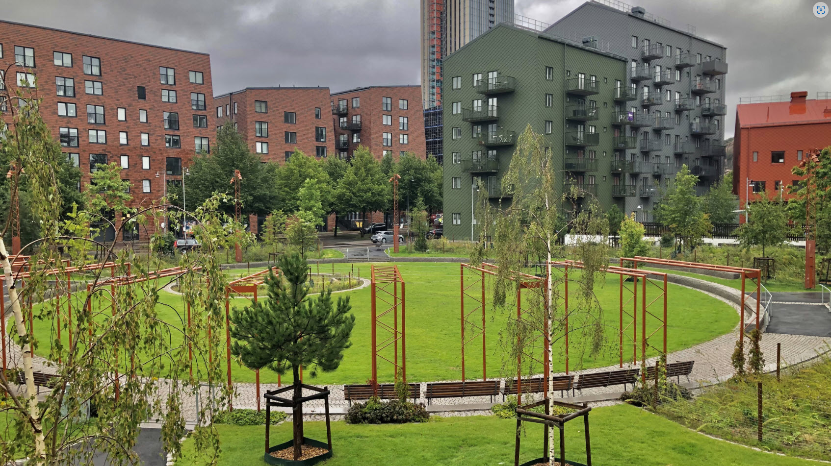 Vy över Maskinparken med gröna ytor och växter och höga hus i bakgrunden