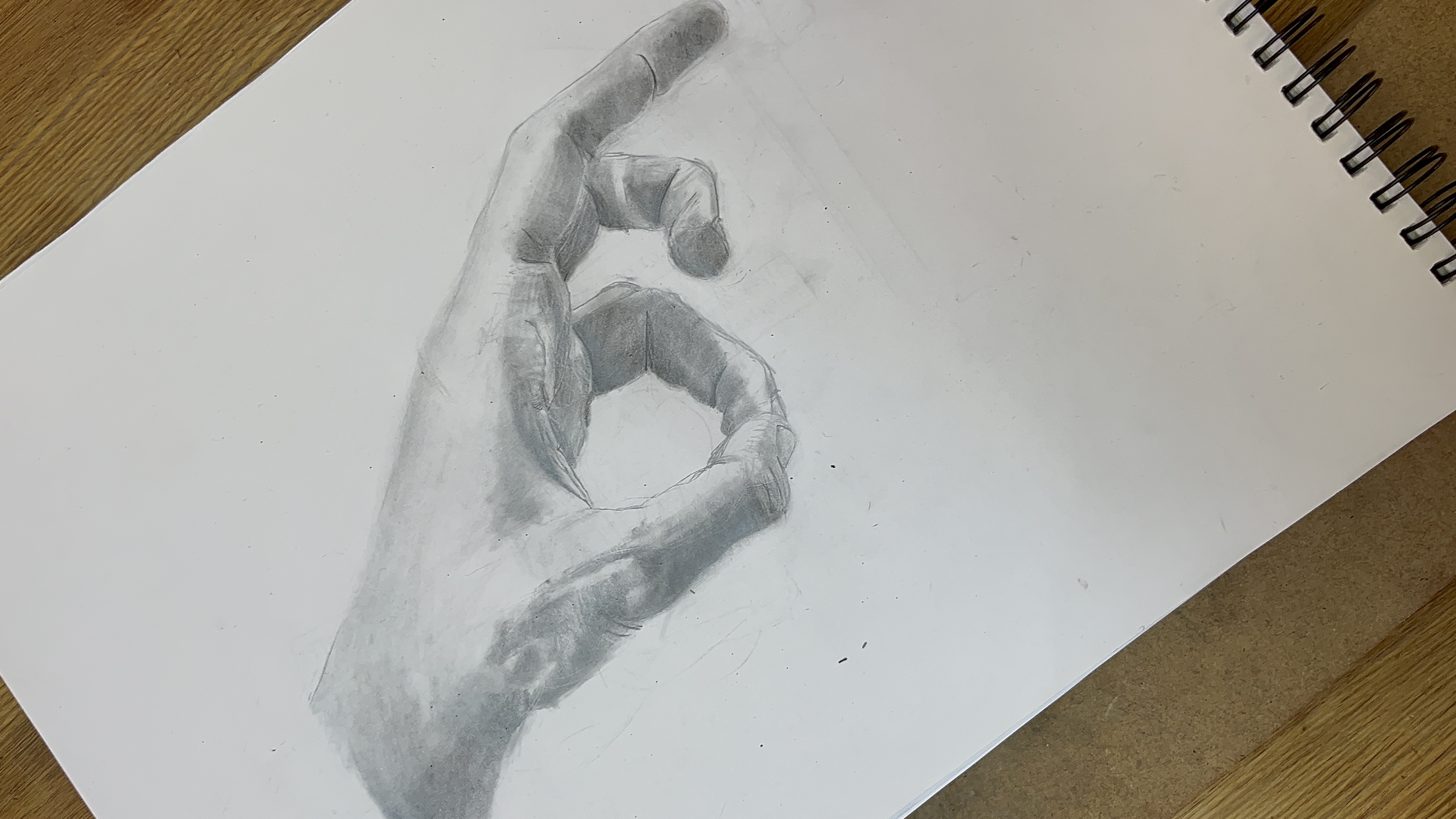 En tecknad hand i blyerts. Handen håller tummen och ringfingret ihop som en ring.