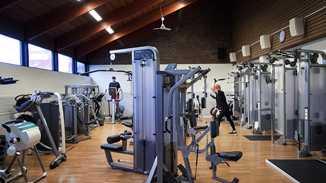 Två personer styrketränar i Kärra simhalls gym.