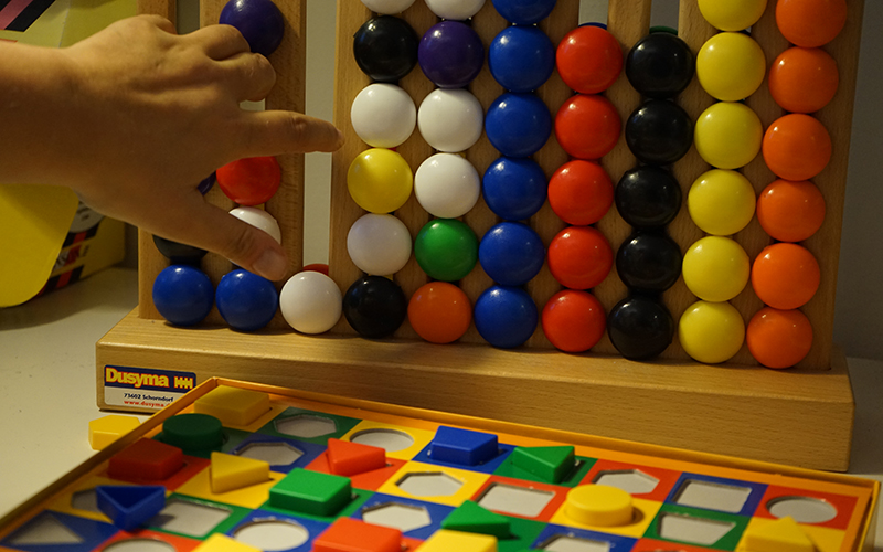 Person använder pedagogiskt redskap i form av färglada kulor på en ram.