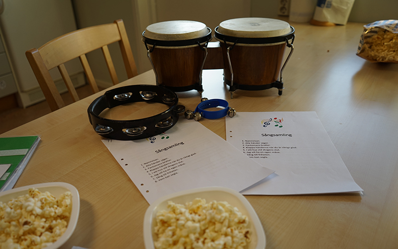 Aktiviteten sångsamling. Ett bord med trummor, en tamburin, sånghäfte och popcorn på.