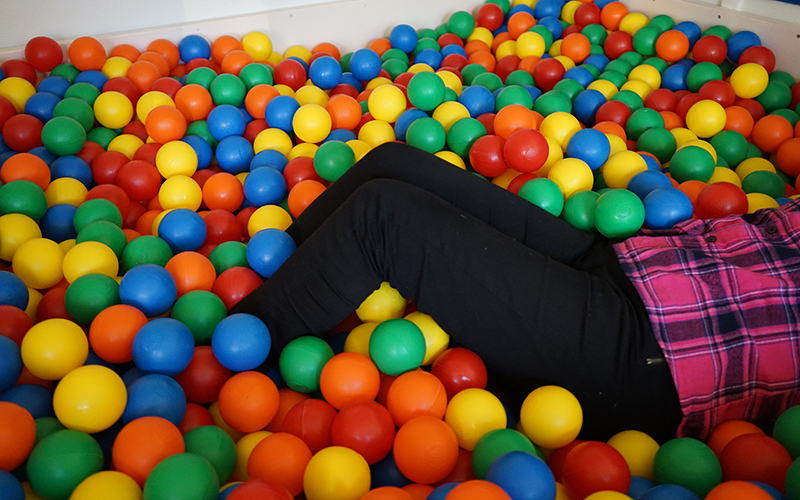 Ett bollhav av färgglada bollar. En person ligger i bollhavet.