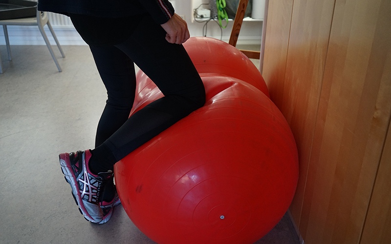 En person lutar benet mot en röd stor boll.