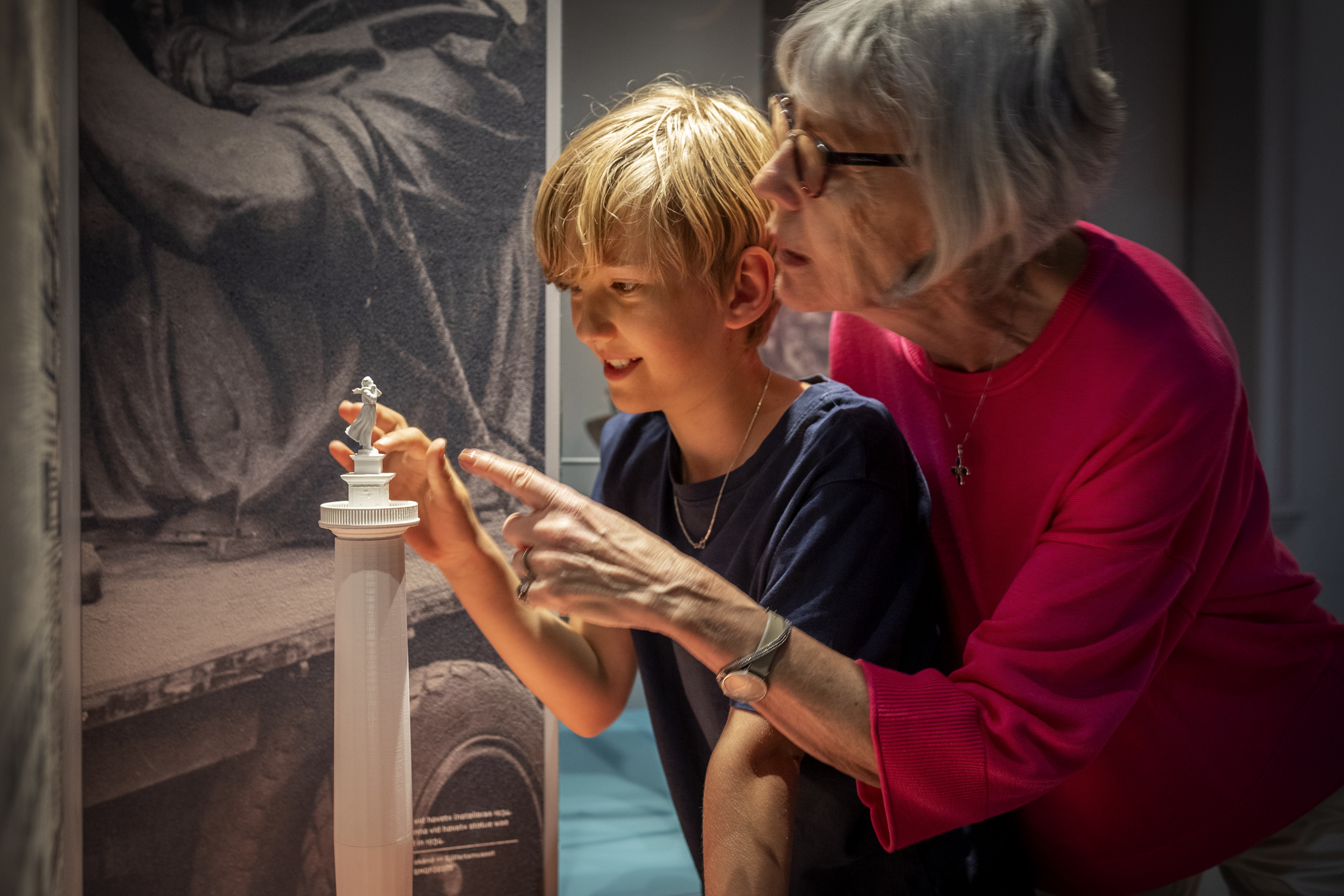 En pojke och en &auml;ldre kvinna tittar p&aring; en avbildning av sj&ouml;manshustrun tillsammans p&aring; G&ouml;teborgs stadsmuseum. Foto: Kristin Lidell