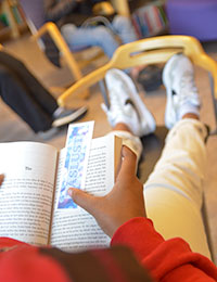 Tonåring, bok och fötter i bibliotek