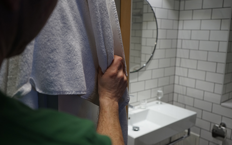 En person hänger upp en handduk in ett badrum.